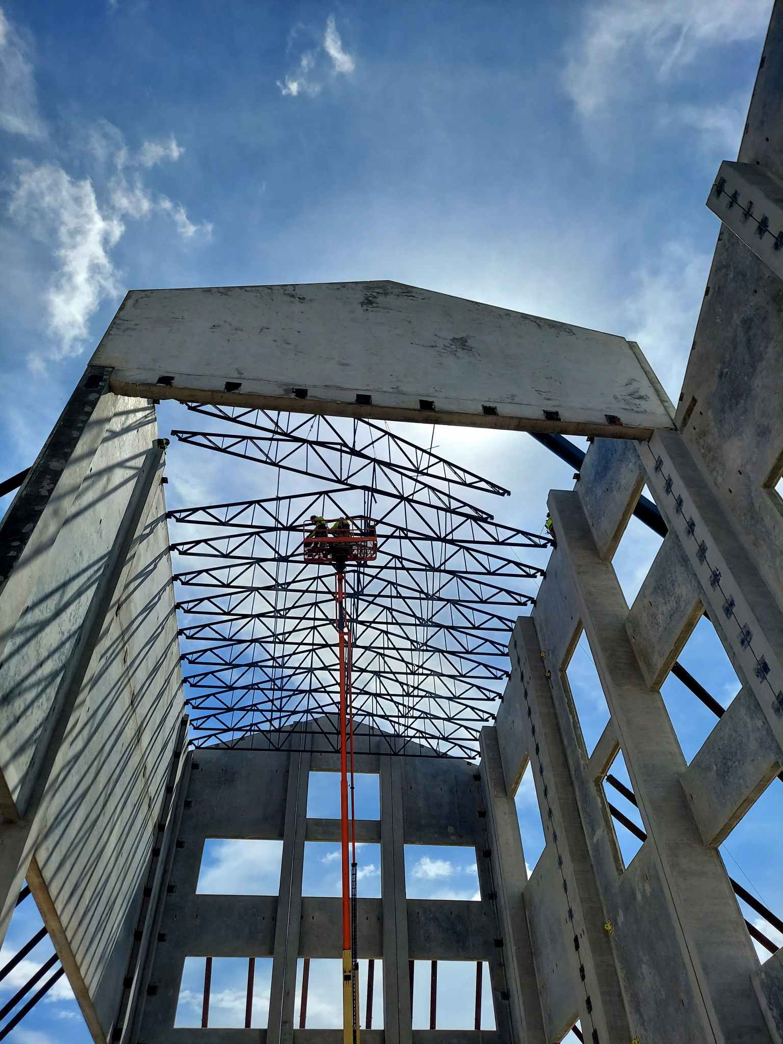 Steel trusses framing blue sky — structural steel erection by Bowman Steel
